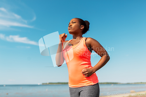 Image of young african american woman running at seaside