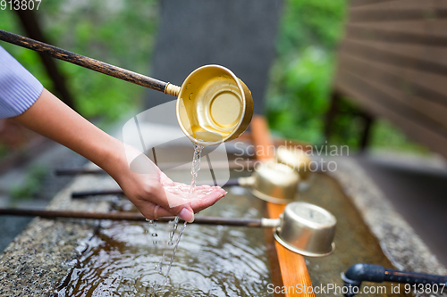 Image of Woman washes her hand in fountain of Japanese temple
