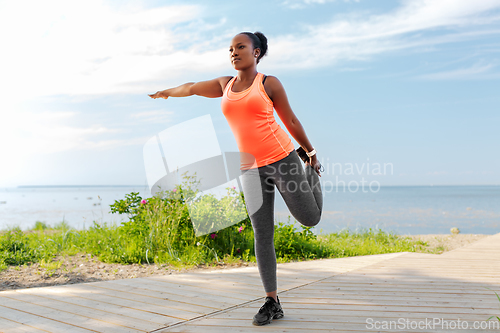 Image of young african american woman exercising on beach