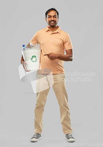 Image of smiling young indian man sorting plastic waste