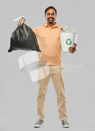 Image of smiling indian man sorting paper and plastic waste