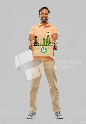 Image of smiling young indian man sorting glass waste