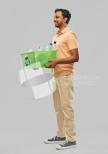 Image of smiling young indian man sorting plastic waste