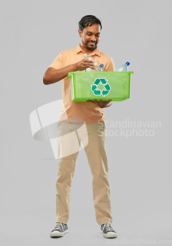 Image of smiling young indian man sorting plastic waste