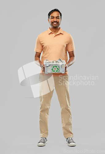 Image of smiling young indian man sorting metallic waste