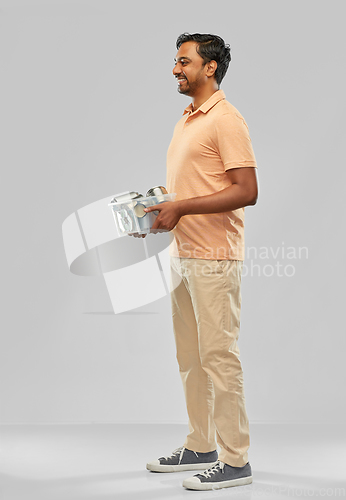 Image of smiling young indian man sorting metallic waste