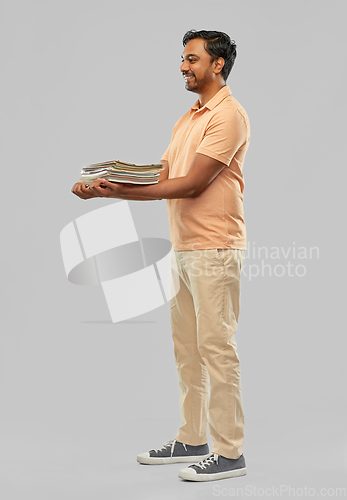 Image of smiling young indian man sorting paper waste