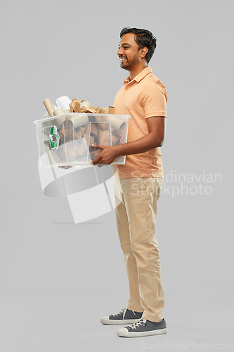 Image of smiling young indian man sorting paper waste