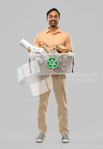 Image of smiling young indian man sorting paper waste