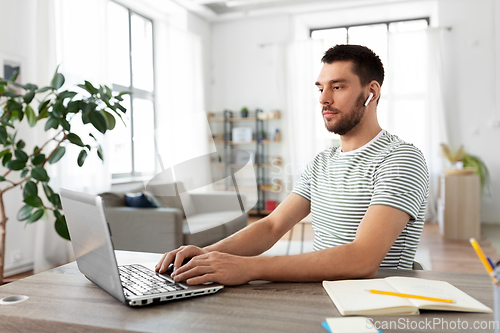 Image of man with laptop and earphones at home office