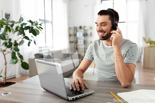 Image of man with headset and laptop working at home