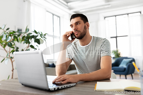 Image of man with laptop calling on phone at home office