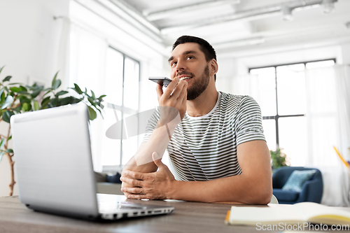 Image of man with laptop calling on phone at home office