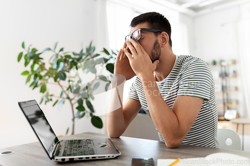 Image of tired man with laptop working at home office