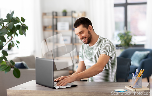 Image of man cleaning laptop with wet wipe at home office