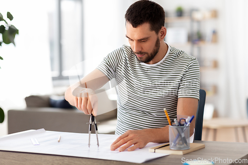 Image of architect with blueprint working at home office