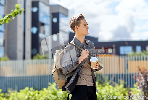 Image of young man with backpack drinking coffee in city