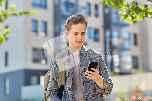 Image of teenage student boy with phone and bag in city