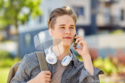 Image of teenage student boy calling on smartphone in city