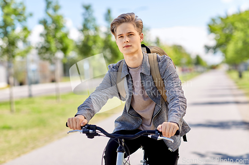 Image of young man riding bicycle on city street