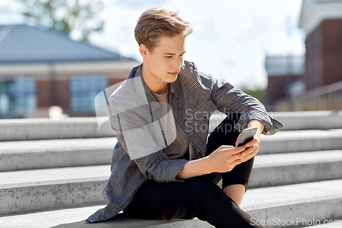 Image of teenage boy using smartphone in city