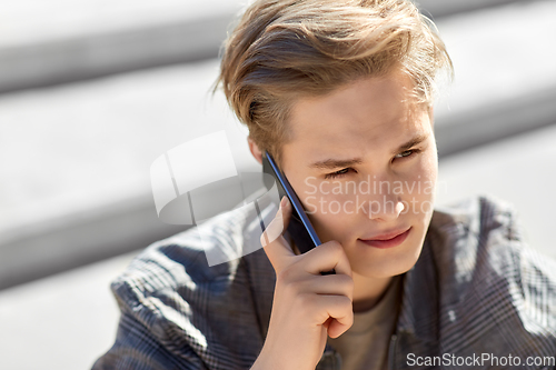 Image of teenage boy calling on smartphone outdoors