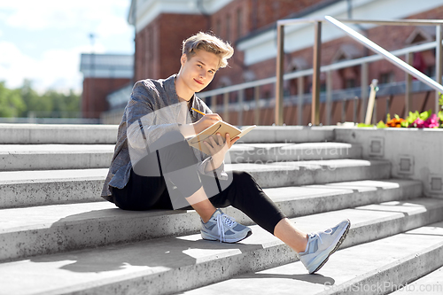 Image of young man with notebook or sketchbook in city