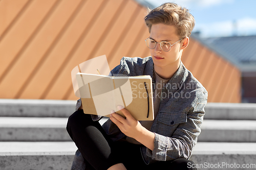 Image of young man with notebook or sketchbook in city