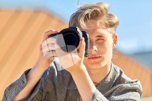 Image of young man with camera photographing outdoors