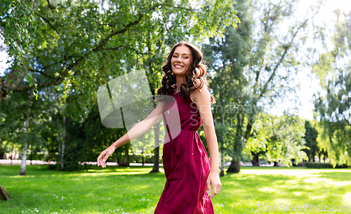 Image of happy smiling woman walking along summer park