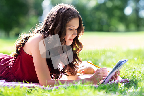 Image of happy woman with diary or notebook at park