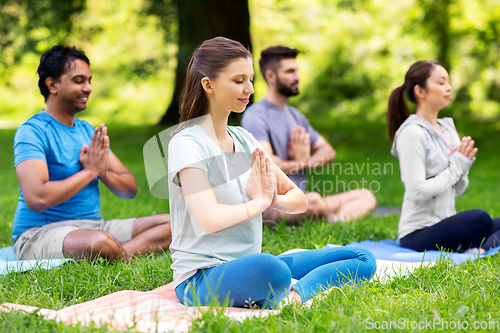 Image of group of happy people doing yoga at summer park