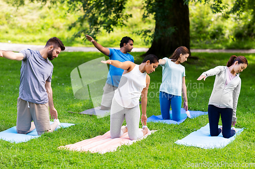 Image of group of people doing yoga at summer park