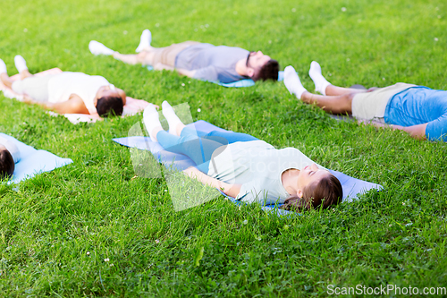 Image of group of people doing yoga at summer park