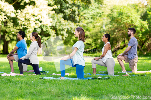 Image of group of people doing yoga at summer park