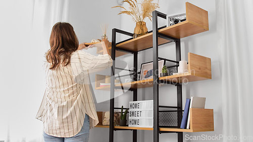 Image of woman placing aroma reed diffuser to shelf home