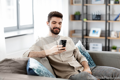 Image of man in earphones listening to music on smartphone