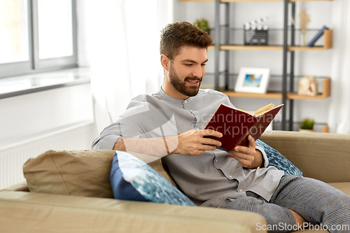 Image of man reading book at home