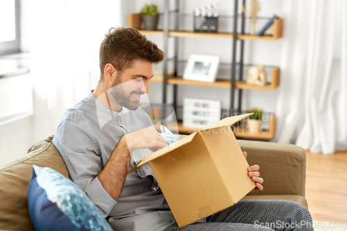 Image of happy man opening parcel box at home