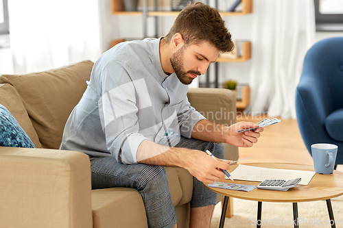 Image of man with money and calculator filling papers