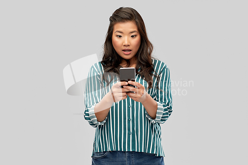 Image of surprised asian woman using smartphone