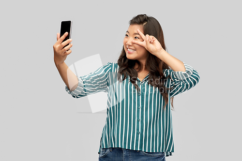 Image of smiling asian woman taking selfie by smartphone