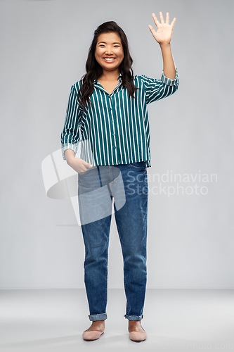 Image of happy smiling asian woman waving hand
