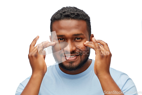Image of happy african american man touching his face