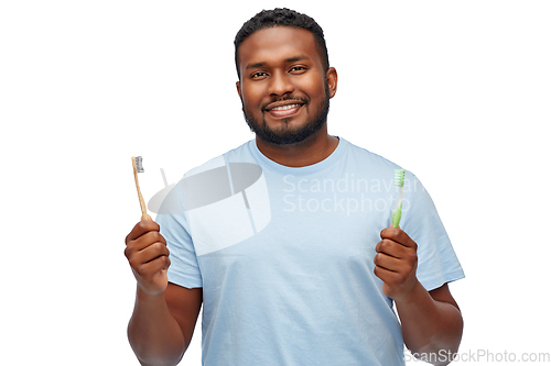 Image of african man with wooden and plastic toothbrushes