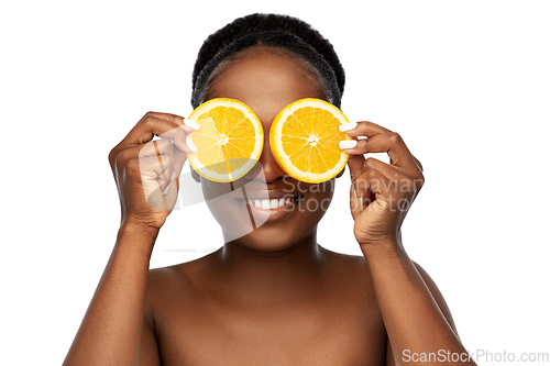 Image of smiling african woman making eye mask of oranges