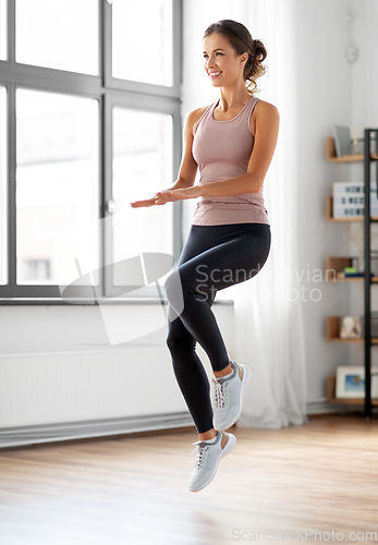 Image of smiling young woman exercising at home