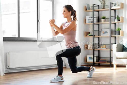 Image of smiling young woman exercising at home