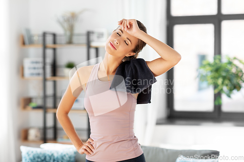 Image of tired young woman with towel after fitness at home
