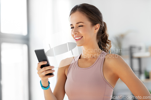 Image of happy woman with smatphone exercising at home